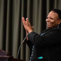 Woman clapping while giving speech at podium